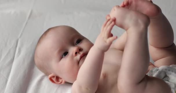 Младенец в сухом подгузнике играет с игрушками — стоковое видео