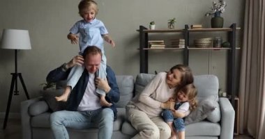 Hamile kadın ve büyük aile kanepeye oturmuş oyun oynuyorlar.