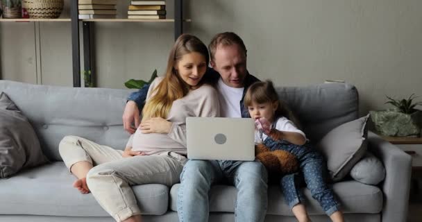 Сім'я з вагітною дружиною чоловік і дочка використовують ноутбук — стокове відео