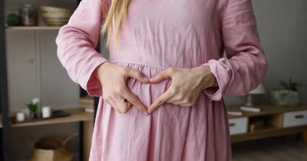 Mujer embarazada hace que la forma del corazón con los dedos en el vientre grande — Vídeos de Stock