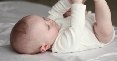 Yakından bak. Yeni doğmuş bebek, takım elbiseli. Yatakta yatıyor.