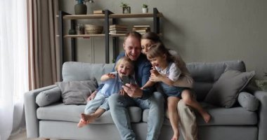 Küçük çocukları olan mutlu bir aile akıllı telefon kullanarak eğleniyor.