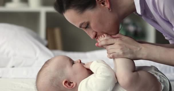 Jeune mère aimante embrasser minuscules orteils de son bébé — Video