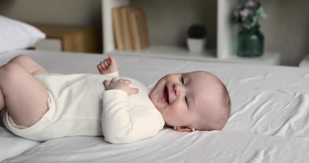 Zoet lachende baby in bodysuit en luier liggend op bed — Stockvideo