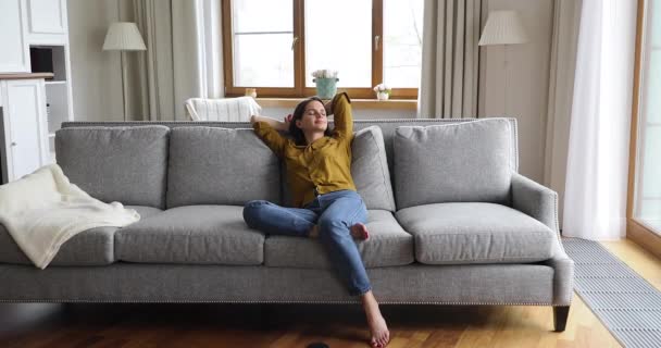 Young woman relaxing on couch inside fashionably furnished apartment — Stock Video