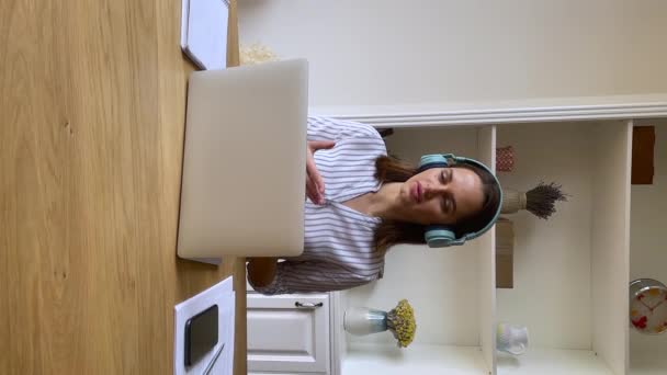 Kulaklık takan genç bir kadın laptopta video çağrısı yapıyor. — Stok video