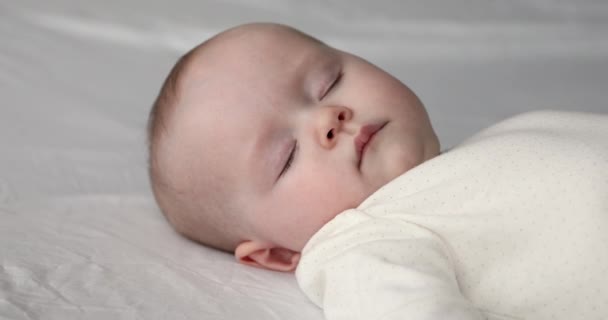 Κοντινό πρόσωπο του γαλήνιου νεογέννητου κοιμάται στο κρεβάτι — Αρχείο Βίντεο