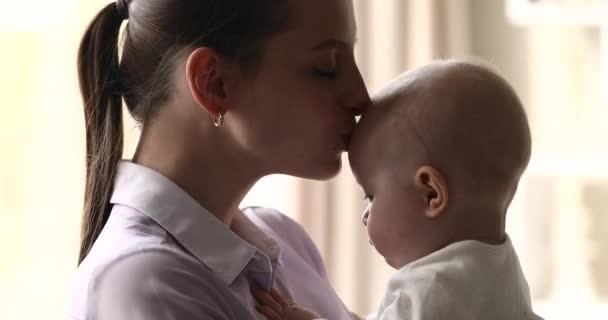 Nahaufnahme liebevolle Mutter hält und küsst niedliches Neugeborenes — Stockvideo