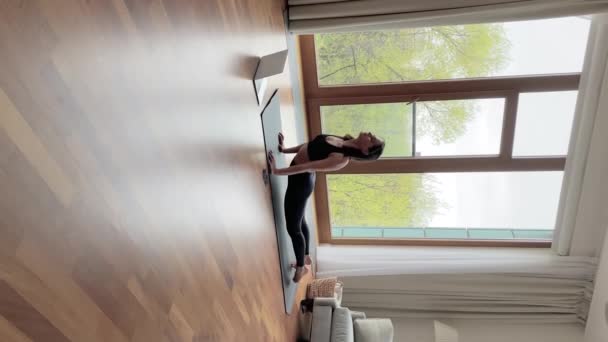 Vertikaler Blick junge Frau macht Yoga-Asanas im Wohnzimmer — Stockvideo