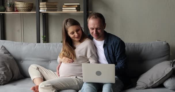 Make kramar gravid fru, med hjälp av laptop diskutera online-köp — Stockvideo