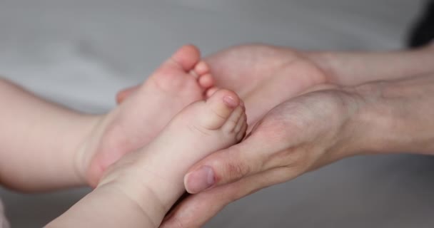 Primer plano amoroso mamá palmas sostiene pequeños dedos de los pies del bebé recién nacido — Vídeo de stock