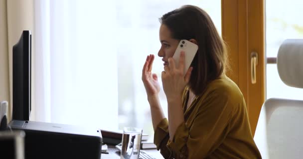 女性はPCのキーボードで電話やテキストメッセージで話します — ストック動画