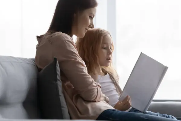 Vårdande ung mor lära små barn dotter läser. — Stockfoto