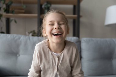 Sevinçten havalara uçmuş küçük bir kız çocuğu gülüyor, samimi duygular gösteriyor..