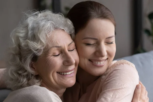 Cerca de tiro en la cabeza devota vieja madre abrazo adulto hija. — Foto de Stock