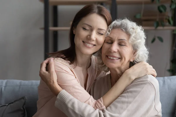Liefdevolle jonge vrouw knuffelen oudere moeder thuis. — Stockfoto