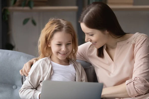 Vårda unga mor lära liten dotter med hjälp av datorprogram apps. — Stockfoto