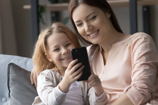 Glad liten unge med smartphone med omtänksam mamma. — Stockfoto