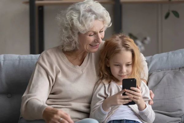 Щаслива бабуся і маленька дівчинка використовує мобільний телефон . — стокове фото