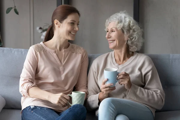 Glad ung kvinna kommunicera med äldre mor hemma. — Stockfoto