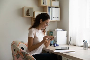 Kadın akıllı telefon kullanarak iş yerinde mola veriyor.