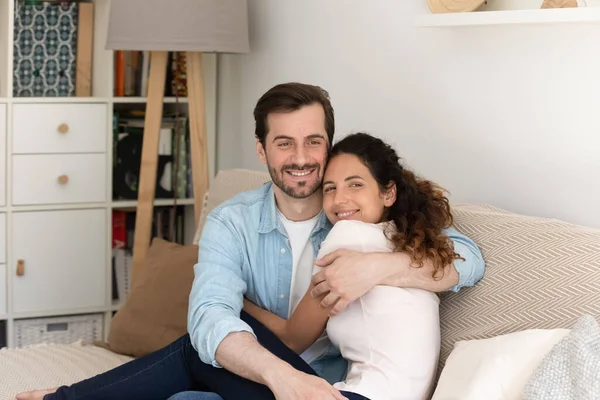 Glückliches Paar umarmt auf Sofa sitzen Lächeln Blick in die Kamera — Stockfoto