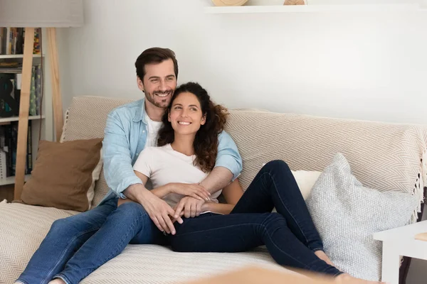 Paar umarmt sich zu Hause und lächelt tagträumend in die Ferne — Stockfoto
