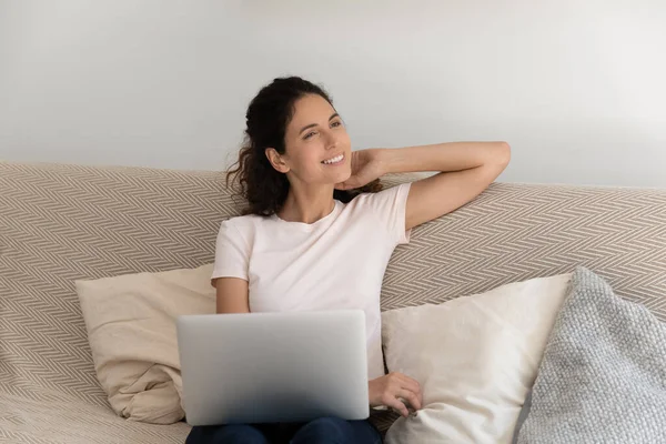 Usmívající se žena relaxovat na gauči v obývacím pokoji s notebookem — Stock fotografie