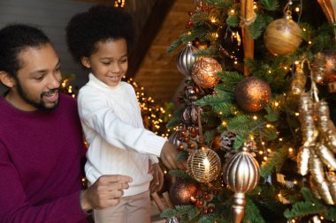 Mutlu çift ırklı baba ve oğul Noel ağacını süsleyin.