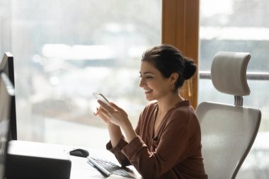 Gülümseyen Hintli bayan şirket çalışanı iş yerindeki telefona cevap veriyor.