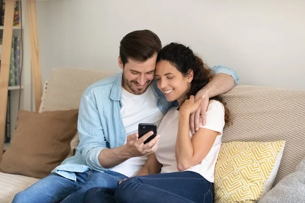 Ζευγάρι αναπαύεται στον καναπέ χρησιμοποιώντας smartphone απολαύσετε online ψώνια — Φωτογραφία Αρχείου