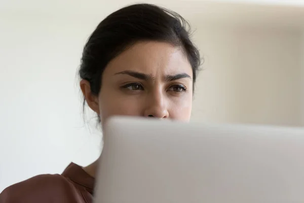 Обличчя серйозної молодої змішаної раси жінки, що працює ноутбуком — стокове фото
