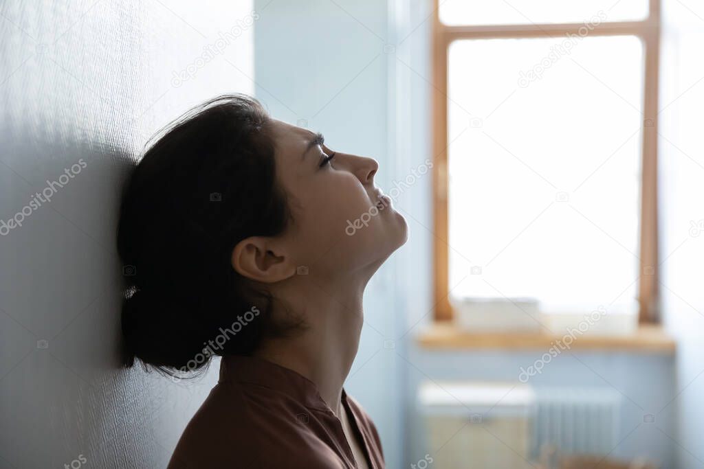 Stressed indian woman with closed eyes sit leaning against wall