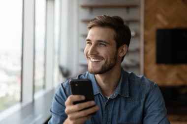 Heyecanlı genç beyaz erkek müşteri modern akıllı telefon kullanıyor
