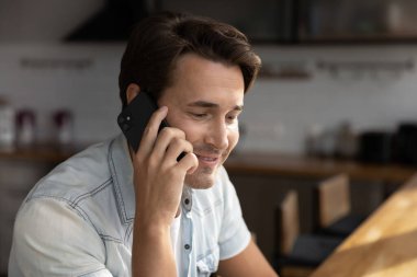 Gülümseyen genç adam akıllı telefon cihazıyla konuşuyor.
