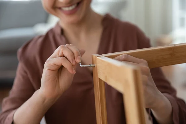 Smiling young female assembling flat pack furniture using hex key — Stock Photo, Image