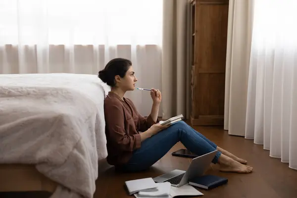 Pensive jonge indiaanse vrouwelijke student zitten op de vloer schrijven essay — Stockfoto