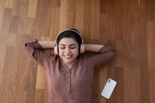 Restful indian female in headset listen to songs on smartphone — Stock Photo, Image