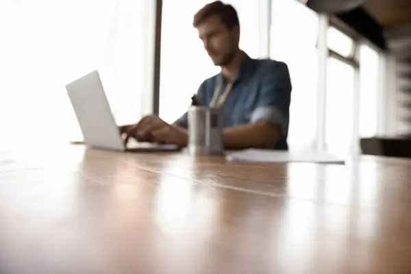 Vista offuscata del dipendente di sesso maschile occupato a lavorare sul computer portatile — Foto Stock