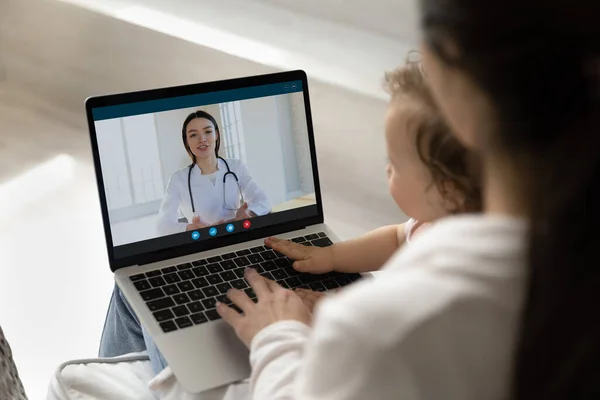 Young pediatrician giving consultation to new mom from laptop screen — Stock Photo, Image