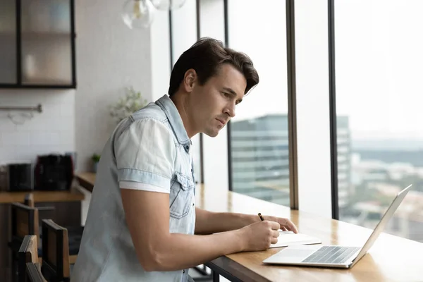 Genç beyaz erkek dizüstü bilgisayar aygıtı kullanarak yazıyor. — Stok fotoğraf