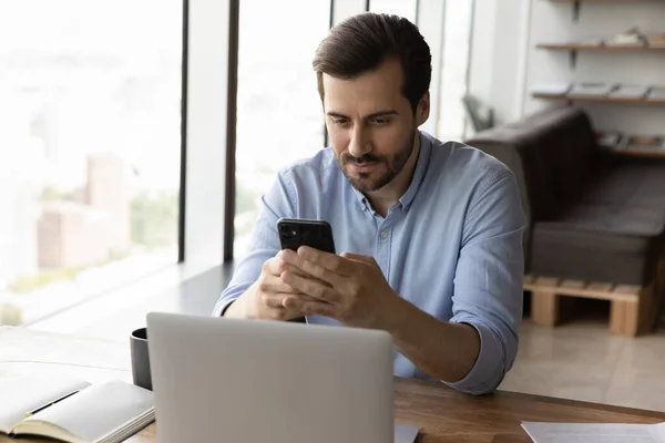 Serieuze mannelijke werknemer gebruik gadgets op de werkplek — Stockfoto