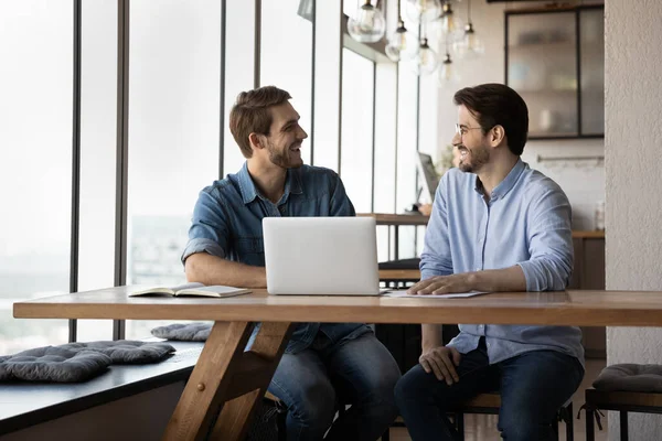 Усміхнені колеги-чоловіки жартують, працюючи разом на комп'ютері — стокове фото
