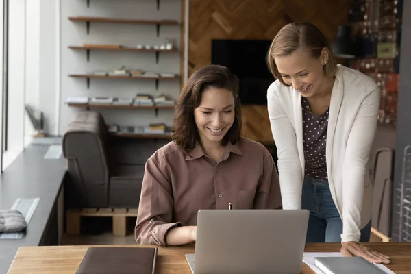 Sonriente caucásica colegas femeninos trabajan juntos en la computadora — Foto de Stock