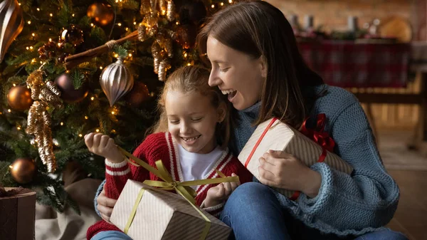 Rindo jovem mãe desembrulhando presentes de Natal com filha pequena. — Fotografia de Stock