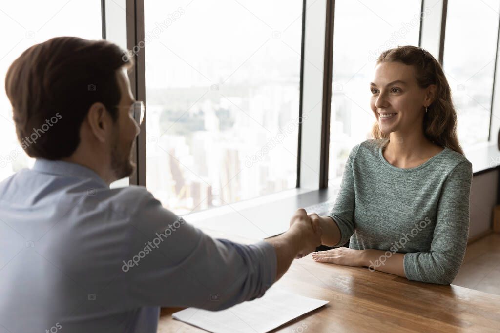 Male boss handshake female applicant at meeting