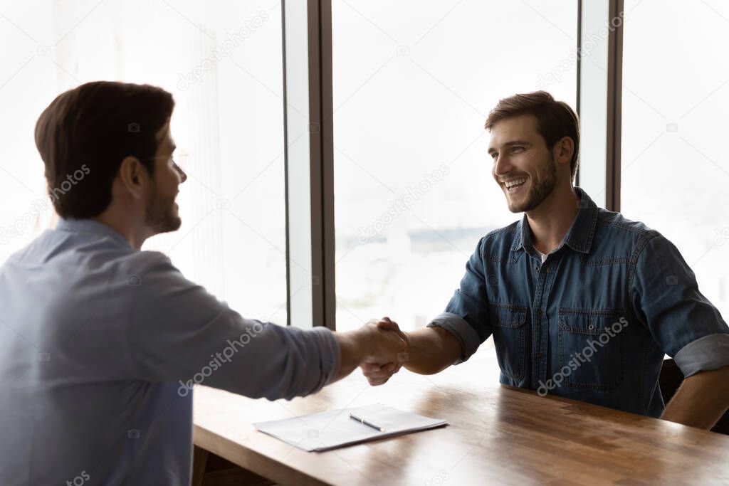 Smiling male employee handshake closing deal at meeting