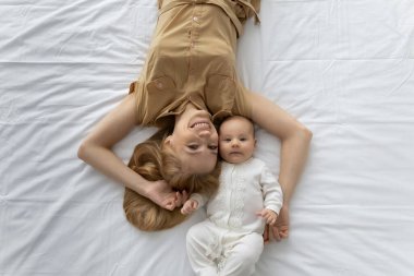 Mutlu genç anne ve sevimli birkaç aylık bebek birlikte dinleniyor.