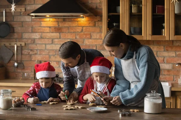 Família feliz com crianças pequenas decorando biscoitos de Natal. — Fotografia de Stock