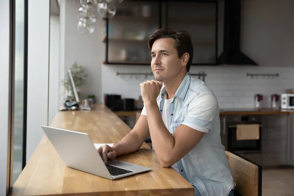 Dromerig mannelijk werk op computer kijken in afstand — Stockfoto